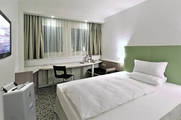 Empfangstresen im Amar Vale Coffeure Salon mit einer Person dahinter, Wandregal mit Nagellackflaschen und Garderobe mit Jacken links.