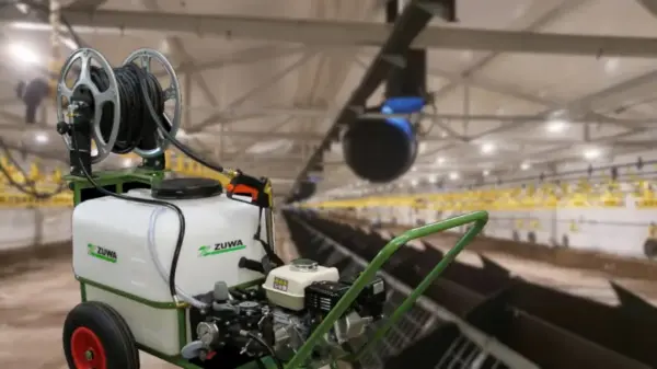 Ein Sprühgerät mit einem angeschlossenen Schlauch steht in einem großen Stall.